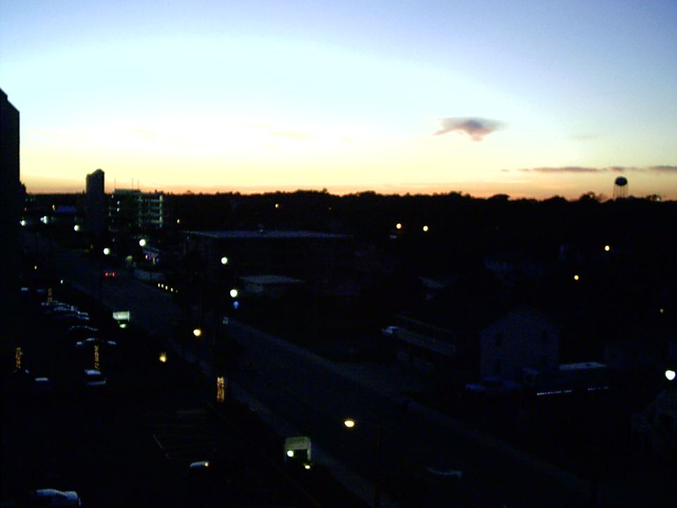 city street and buildings at dusk with a water tower in the distance