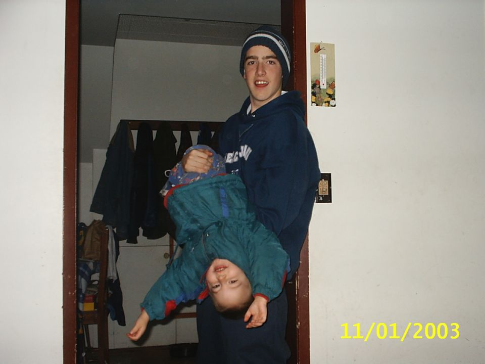 Teenager holding a baby upside down indoors