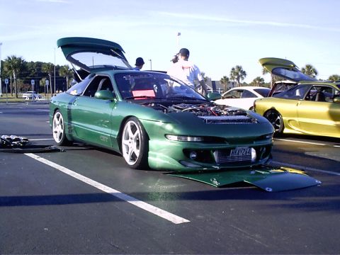 1995 Ford Probe - A modified green 1995 Ford Probe is displayed with its hood and trunk open, revealing the engine and interior.