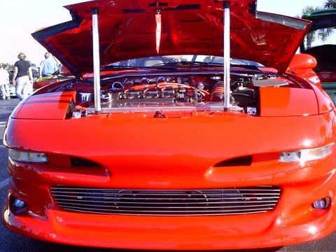 1995 Ford Probe - A red 1995 Ford Probe is displayed with its hood open, revealing the engine bay and custom grille.