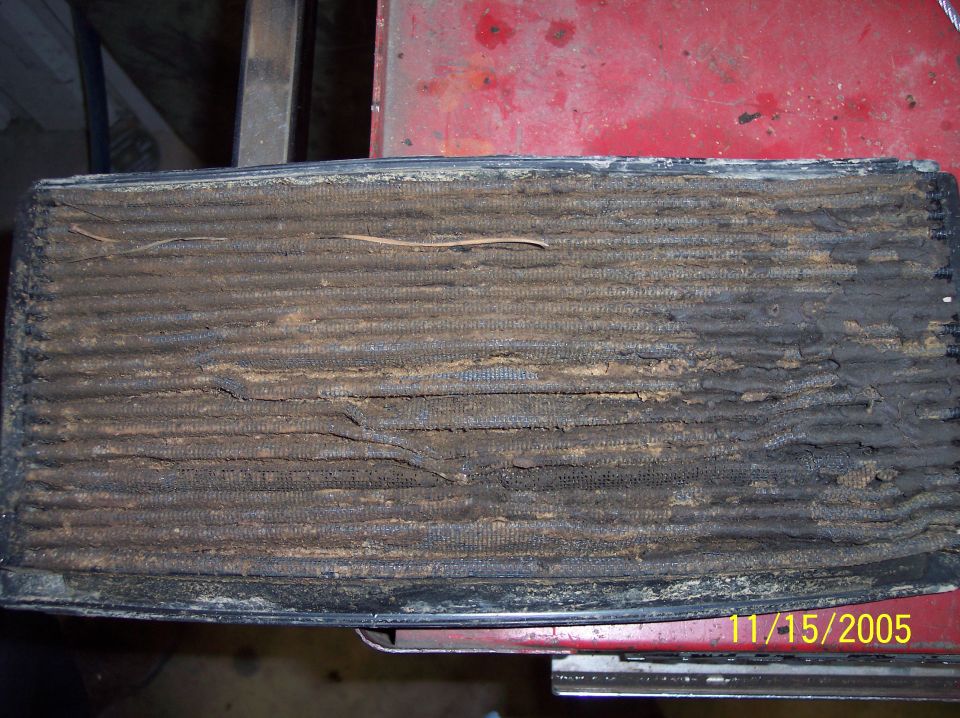 Removed radiator with fins completely packed with dried mud and debris on a red tool box
