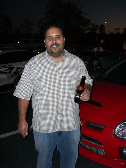 1996 Ford Probe - A man stands next to a red Dodge SRT-4 in a parking lot at dusk.