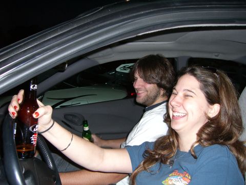 1996 Ford Probe - Two people are inside a car, one holding a beer bottle and laughing while the other looks on.
