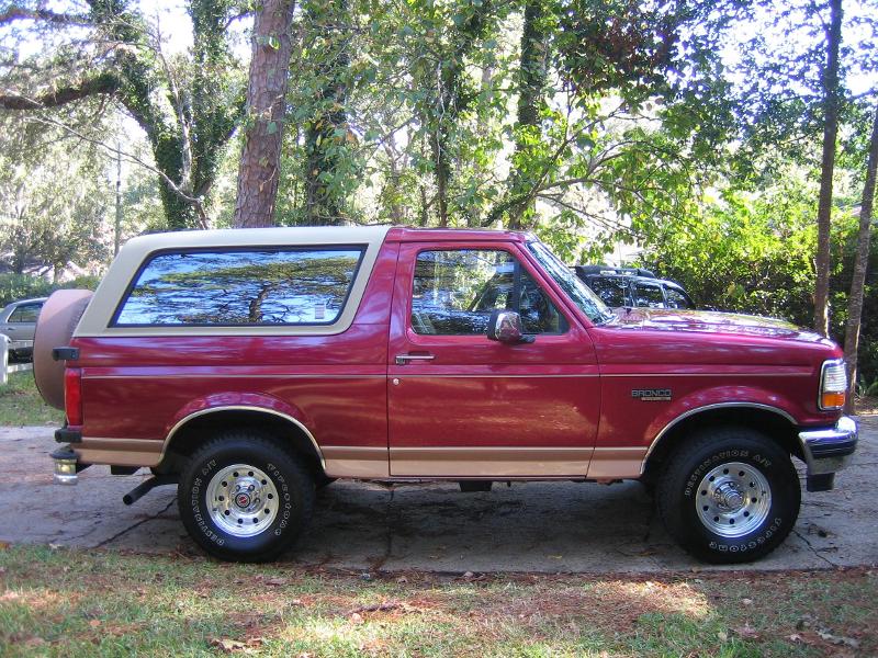 1994 Ford Bronco, red with tan trim, side view. Spare tire mounted on rear door