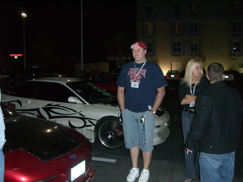 1996 Ford Probe - A white 1996 Ford Probe with custom tribal graphics is parked next to a red car at night.