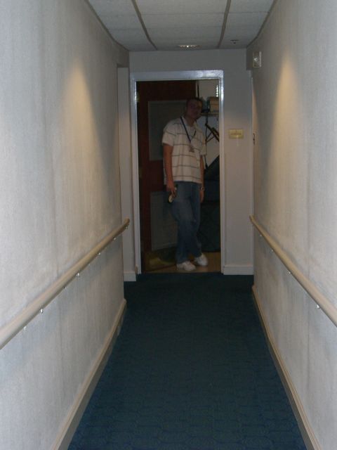 1996 Ford Probe - A man stands in a doorway at the end of a carpeted hallway with handrails on the walls.
