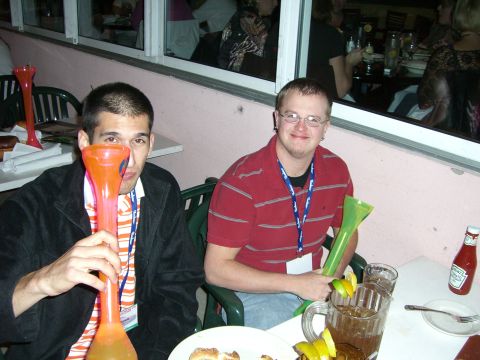 1996 Ford Probe - Two men are seated at a table with drinks and food, holding large novelty drinking vessels.