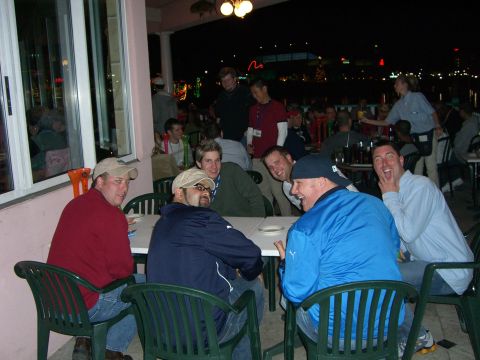 1996 Ford Probe - A group of men are gathered around tables outdoors at night, with some laughing and interacting.