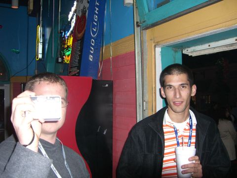 1996 Ford Probe - Two men are in a bar, one taking a photo while the other holds a drink.