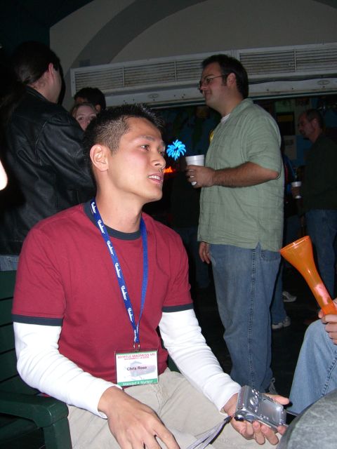 1996 Ford Probe - Attendees mingle at an indoor event, with one man holding a digital camera.