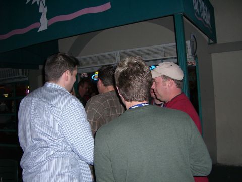1996 Ford Probe - A group of men are conversing near the entrance of a building with a distinctive awning.