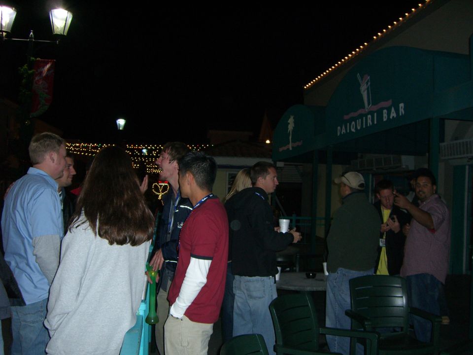 Group of people gathered outside a bar at night, with awnings reading "DAIQUIRI BAR"