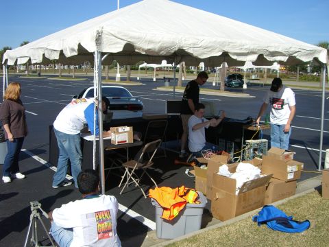 1996 Ford Probe - A white sports car is visible in the background behind a tent where people are gathered.
