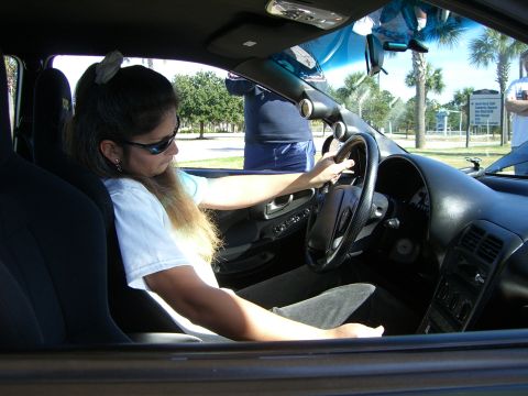1996 Ford Probe - A woman sits in the driver's seat of a car, her hands on the steering wheel, with aftermarket gauges visible on the dashboard.