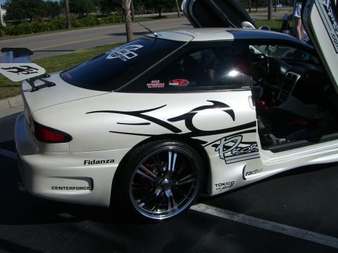 1996 Ford Probe - This heavily modified white coupe features butterfly doors and prominent racing decals, including the word 'PROBE' on its side.