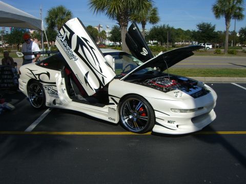 1996 Ford Probe - This heavily modified white sports car features custom graphics, butterfly doors, and an exposed engine bay.