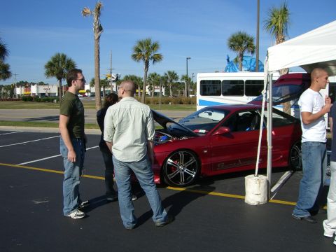 1996 Ford Probe - People gathered around a red 1996 Ford Probe with its hood open at an outdoor event.