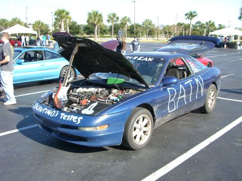 1996 Ford Probe - A blue 1996 Ford Probe is parked with its hood and trunk open, displaying a guitar in the engine bay.