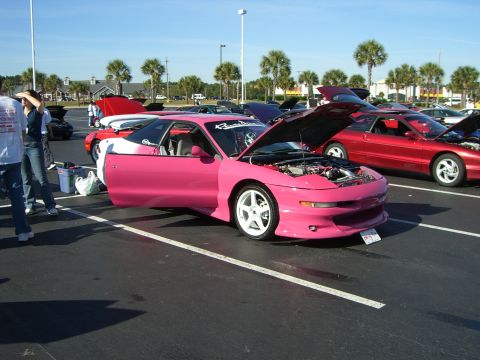 1996 Ford Probe - A bright pink 1996 Ford Probe is displayed with its hood and driver's door open at an outdoor car show.