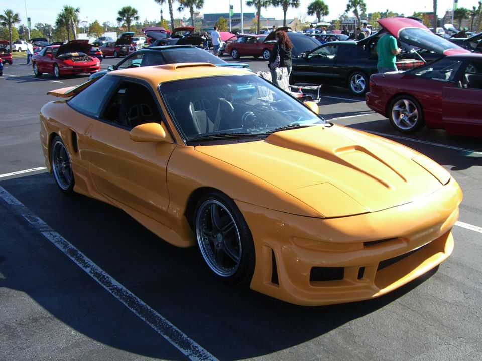 Yellow sports car with custom body kit and hood scoop, parked in a lot