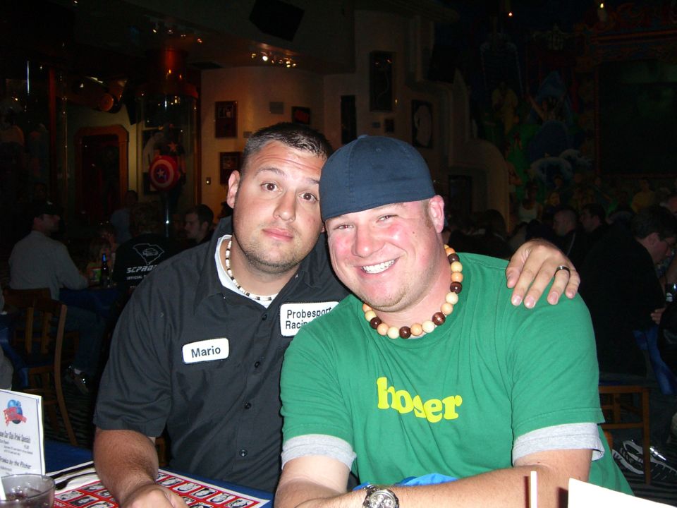 Two men posing for a photo, one wearing a black shirt with a 'Mario' name tag and 'Probesport Racing' text