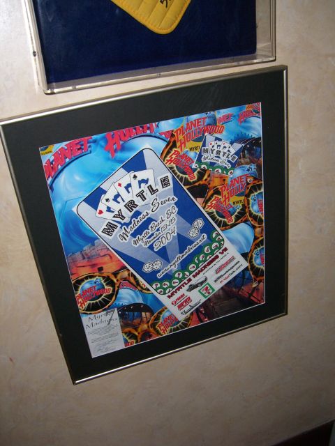1996 Ford Probe - A framed poster for Myrtle Madness, dated November 2004, Planet Hollywood branding.