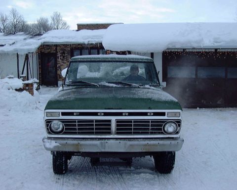 1985 Ford F-150 - A green Ford truck sits parked in the snow, facing the camera directly.