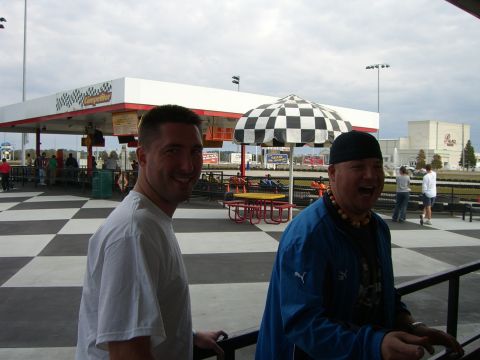 1996 Ford Probe - Two men are enjoying a day at a go-kart track, with a distinctive checkered pattern on the ground and umbrella.