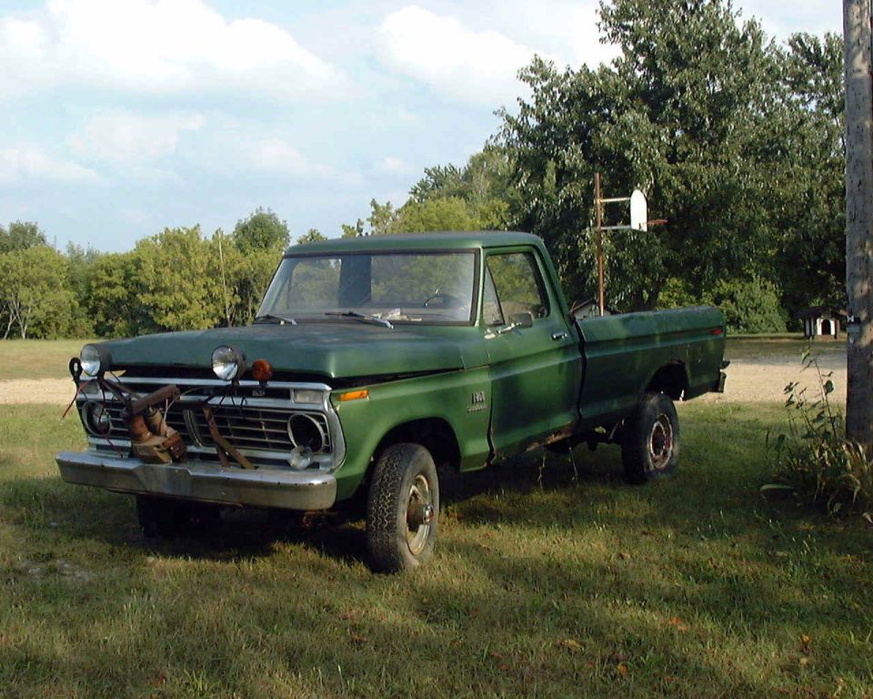Green 1970s Ford F-series pickup parked on grass in a rural yard