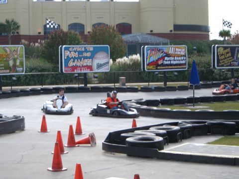1996 Ford Probe - Go-karts race around a track with advertising billboards visible.