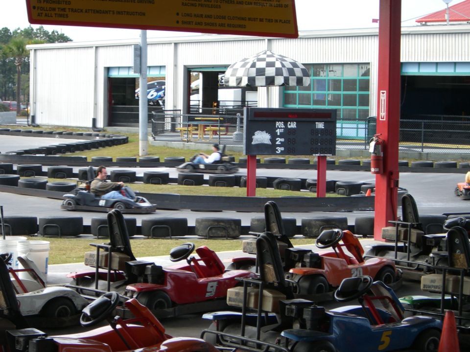 Go-karts parked and on a track at an outdoor amusement park