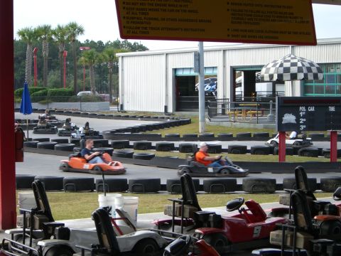 1996 Ford Probe - Go-karts race around a track, with spectators and a building visible in the background.