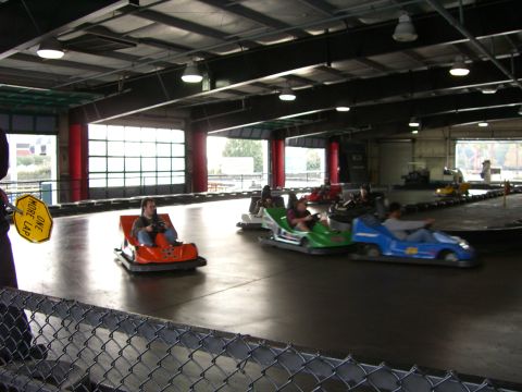 1996 Ford Probe - People are enjoying bumper cars on an indoor track with multiple cars in motion.