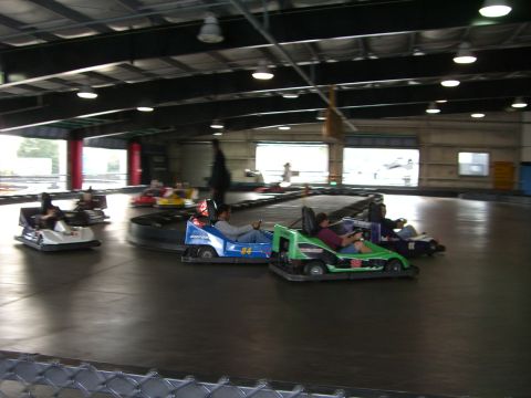 1996 Ford Probe - Several go-karts are in motion on an indoor track, with drivers focused on the race.