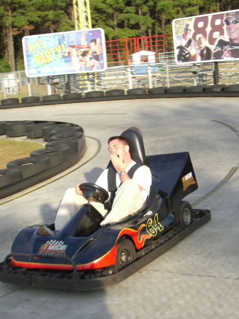1996 Ford Probe - A driver yawns while operating a go-kart on a race track, with billboards in the background.