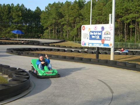 1996 Ford Probe - Person driving a go-kart on a track, with a sign for 'Broadway at the Beach' in the background.