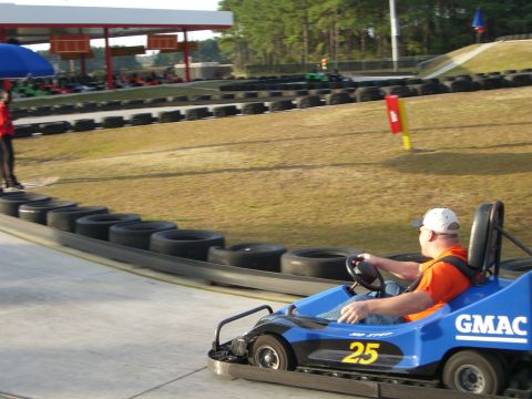 1996 Ford Probe - A man drives a go-kart with the number 25 and GMAC branding around a turn on a race track.