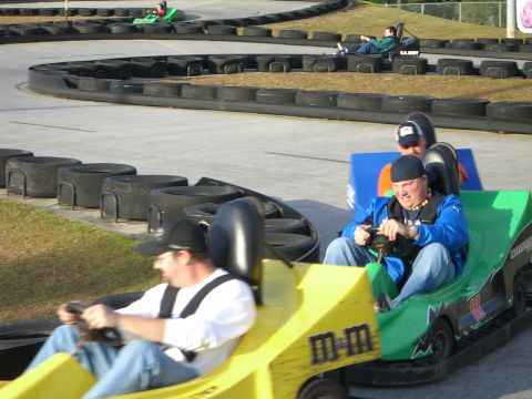 1996 Ford Probe - Several go-karts are in motion on a winding track, with drivers focused on the race.