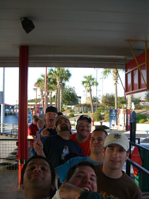 1996 Ford Probe - A group of men stand in line outdoors, with palm trees and a checkered flag visible in the distance.
