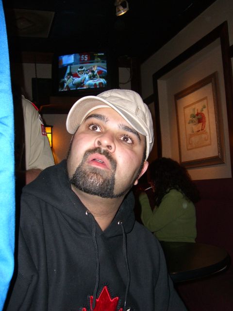 1996 Ford Probe - A man in a black hoodie and baseball cap is the focus, with a football game playing on a TV in the background.