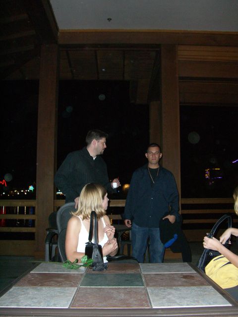 1996 Ford Probe - A group of people are socializing around a table outdoors at night, with distant lights visible.