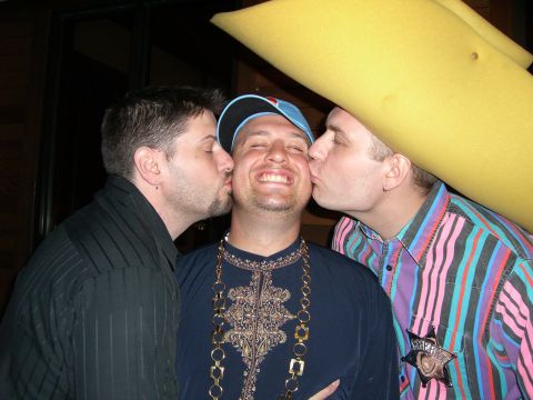 1996 Ford Probe - A humorous scene captures three men in a playful moment, with two men kissing the one in the middle.