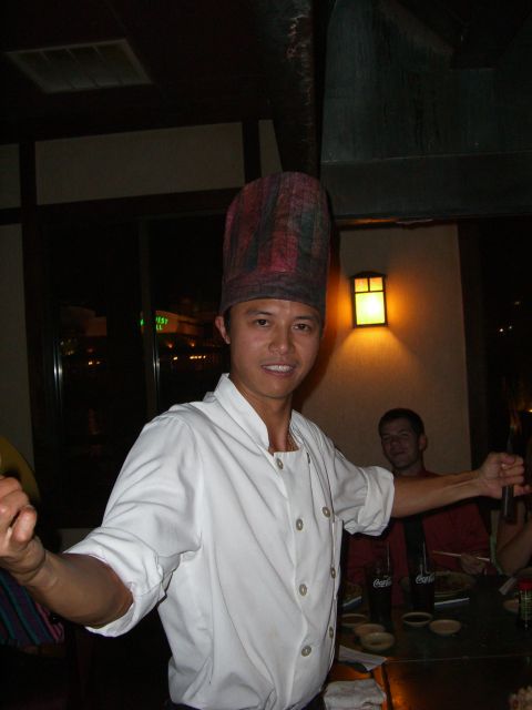 1996 Ford Probe - A chef wearing a tall, checkered hat and white uniform stands with his arms outstretched in a restaurant setting.