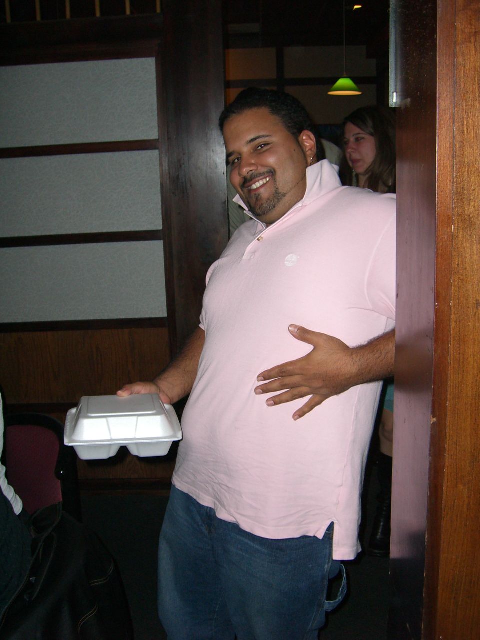 Man in pink polo shirt holding takeout container