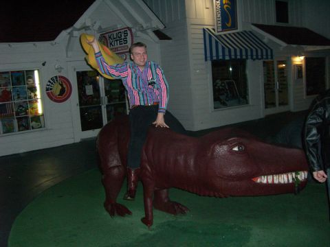 1996 Ford Probe - A man poses atop a dinosaur statue outside a shop at night.