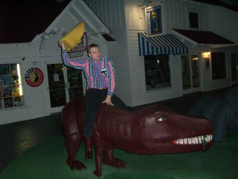 1996 Ford Probe - Man rides a dinosaur statue outside a store at night.