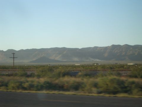 1996 Ford Probe - A wide view of a desert landscape mountains in the distance, railroad tracks, and sparse vegetation under a clear blue sky.