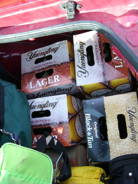 1996 Ford Probe - The trunk of a red vehicle is filled with several crates of Yuengling Lager and Black & Tan beer, along with luggage.