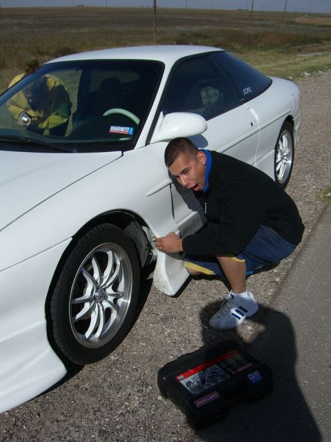 1996 Ford Probe - Man inspects the fender of a white 1996 Ford Probe, with a toolbox nearby.