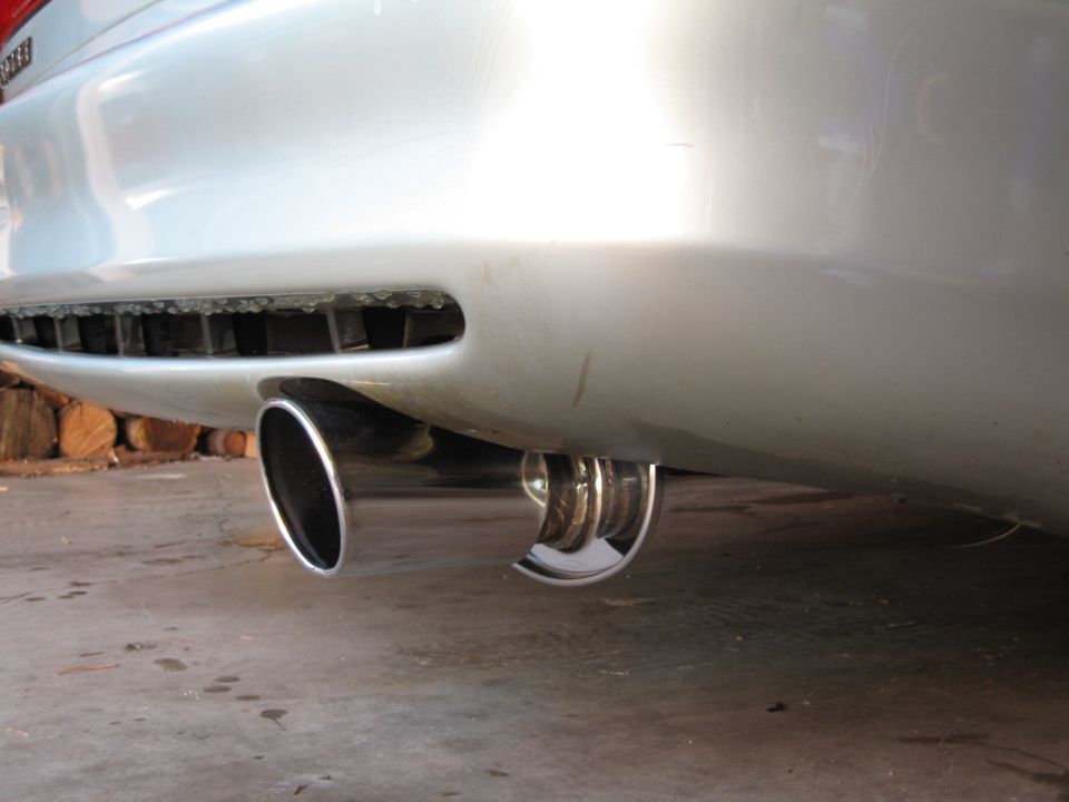 Close-up of dual chrome exhaust tips exiting the rear bumper of a silver car